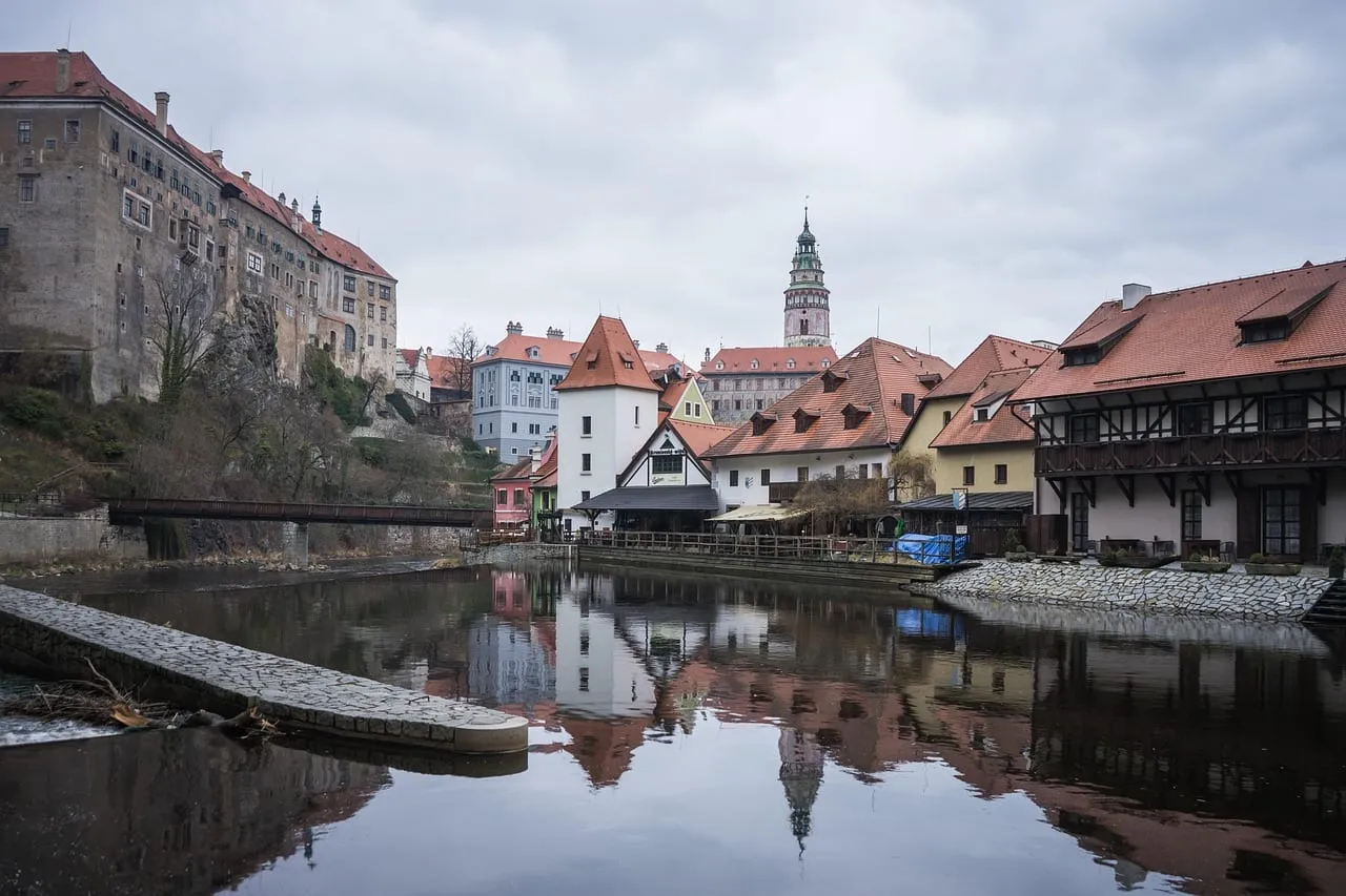 Alte Häuser, gespiegelt in der Moldau, dahinter der Schlossturm