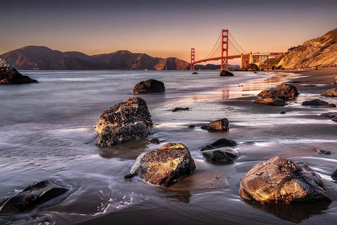 Die Brücke bei Sonnenuntergang, von einem felsigen Strand aus gesehen