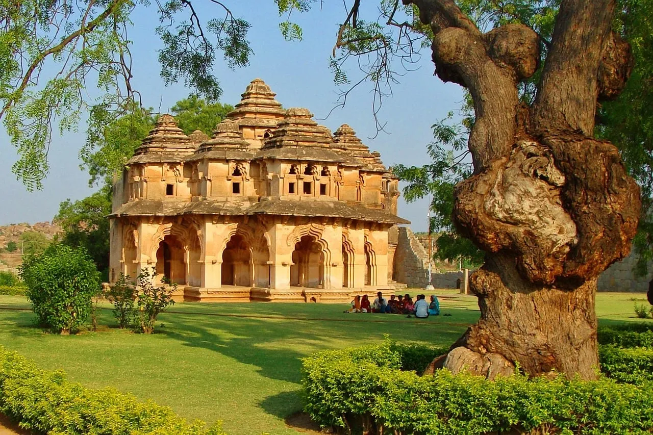 Der Lotus Mahal mit seinen gestuften Bögen neben einem großen alten Baum
