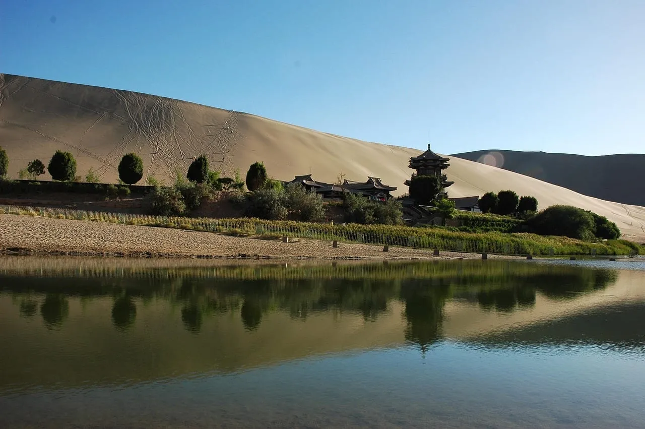Der Crescent Lake mit seinem Pavillon unterhalb der Sanddünen bei Dunhuang