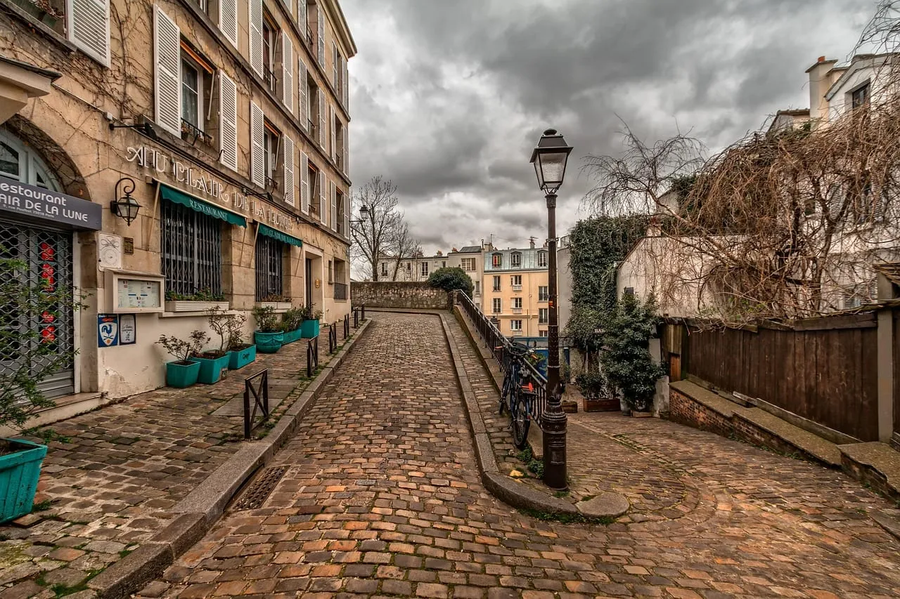 Eine gepflasterte Gasse in Montmartre mit alten Laternen und Häusern
