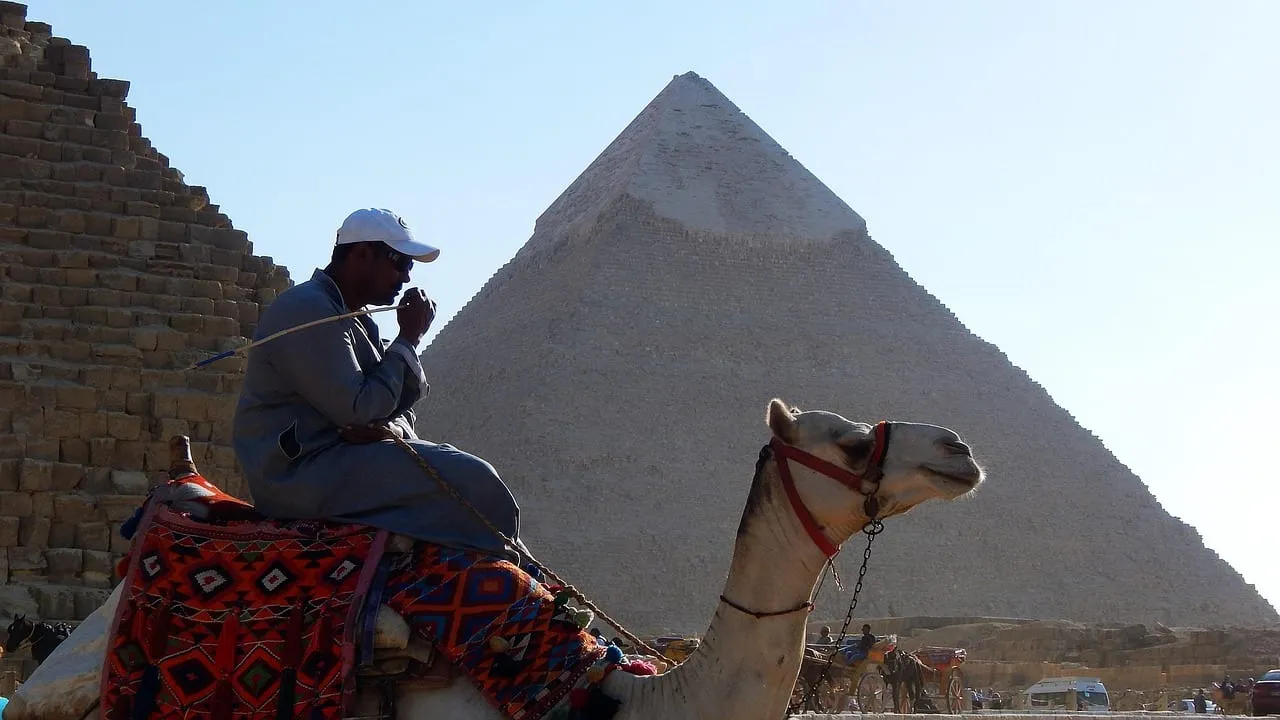 Ein Kamelführer rastet neben einer Pyramide