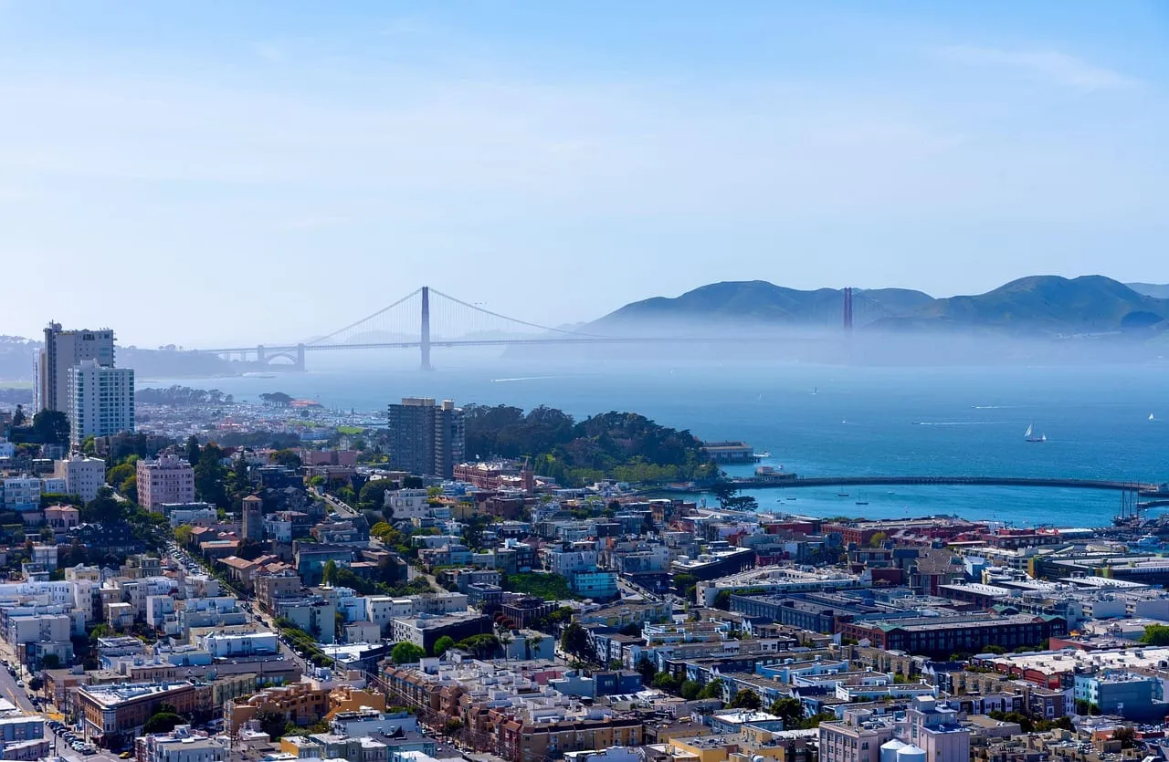 Häuser an einem Hügel in San Francisco, dahinter die Golden Gate Bridge im Nebel