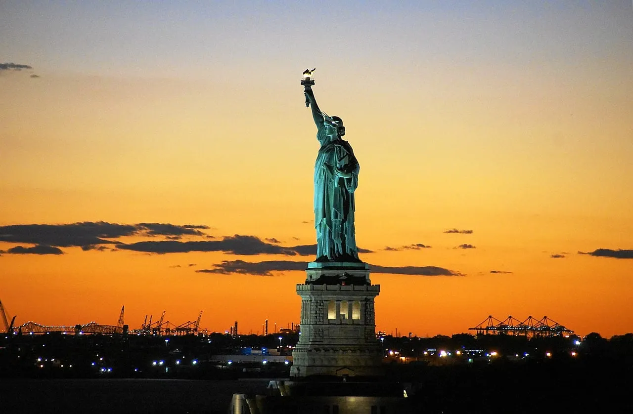 Die Freiheitsstatue als Silhouette vor einem orangefarbenen Sonnenuntergang