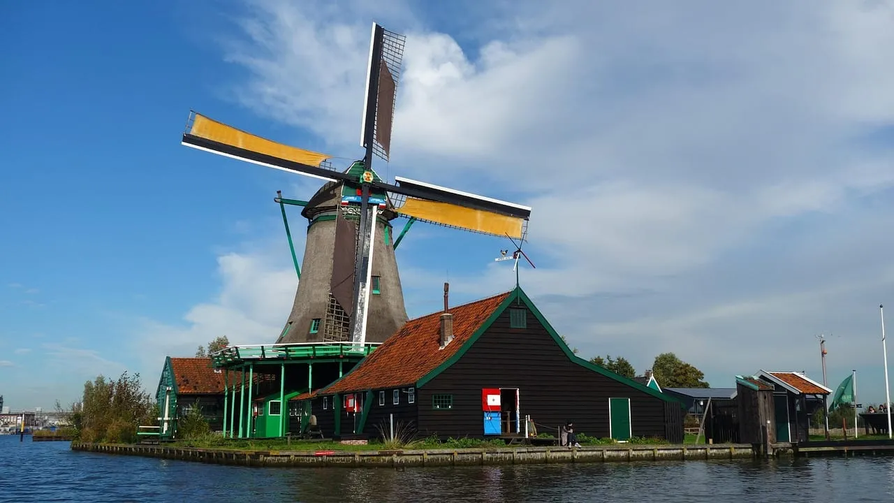 Eine Windmühle mit gelben Flügeln am Wasser